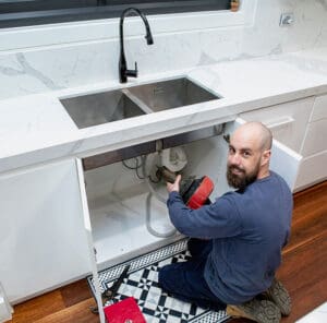 Fast Plumber in action under a Montrose kitchen sink attending to plumbing issues.