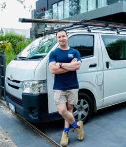 Fast plumber standing proudly with folded arms beside his professional plumbing van in Croydon, Victoria.