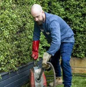 A plumber clearing a blocked drain.