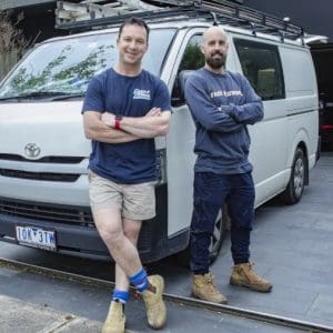 Friendly Malvern East plumber duo standing proudly in front of their plumbing van.