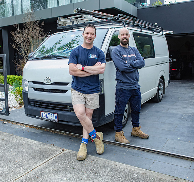Friendly Fast plumber duo standing proudly in front of their plumbing van.