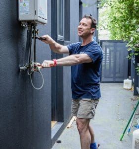 Professional plumber showcasing an instant hot water system installation in a residence house.