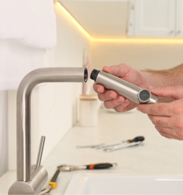 Plumber repairing water tap in kitchen