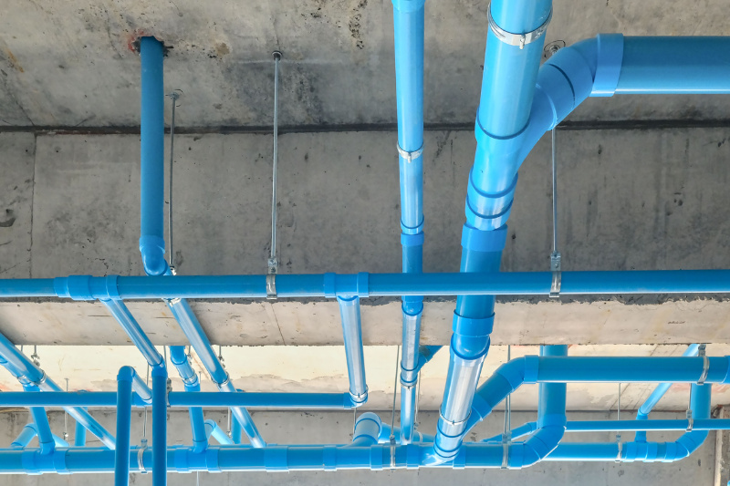 A low angle shot of industrial blue pipes on a ceiling.